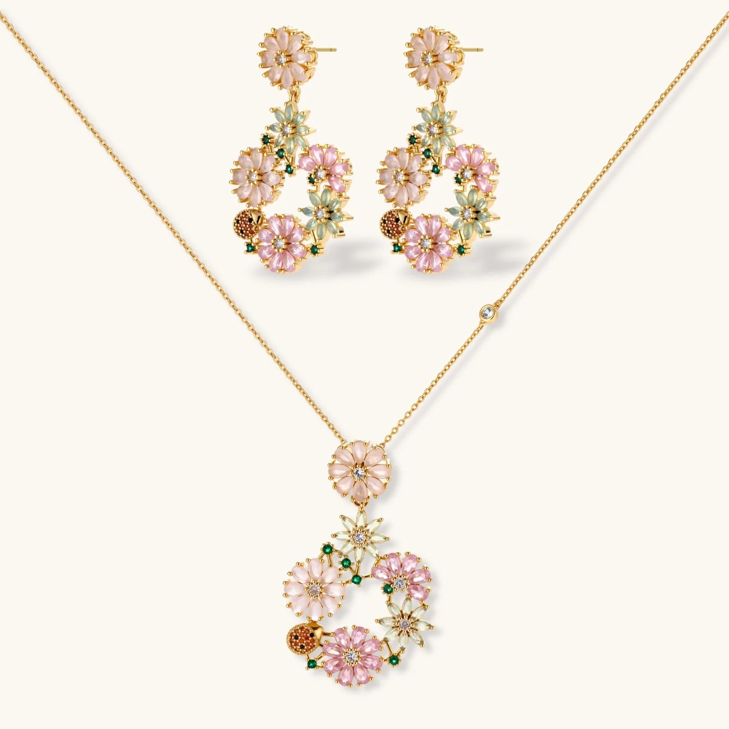 14K gold plated jewelry set with pink and green cubic zirconia flowers arranged in wreath design on cream background
