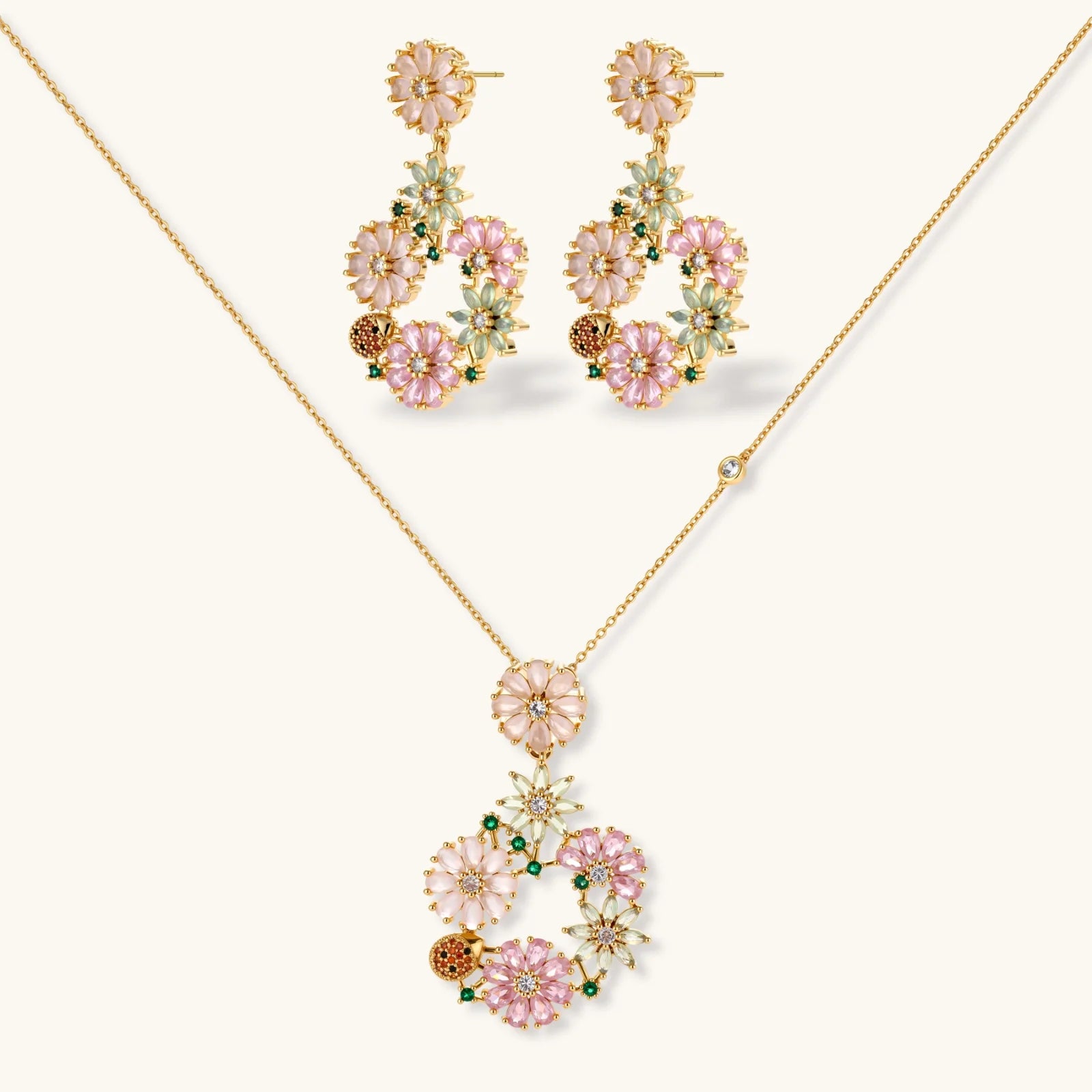 14K gold plated jewelry set with pink and green cubic zirconia flowers arranged in wreath design on cream background