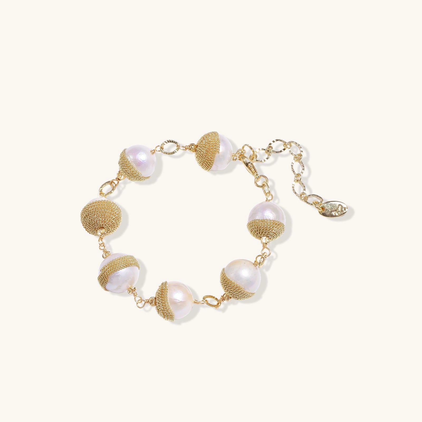 Adjustable bracelet with baroque pearls wrapped in delicate gold mesh netting connected by textured chain links