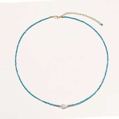 Delicate gold vermeil necklace with teal apatite beads and freshwater pearl on white background.