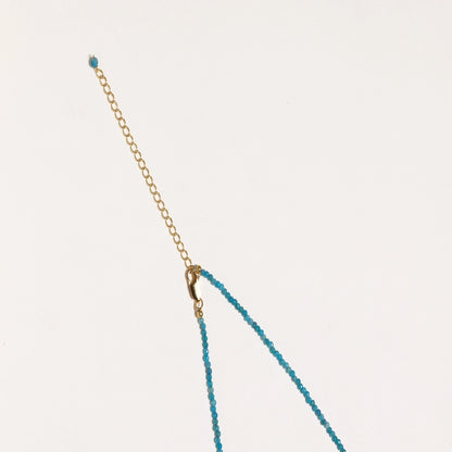 Delicate gold vermeil necklace with teal apatite beads and freshwater pearl on white background.