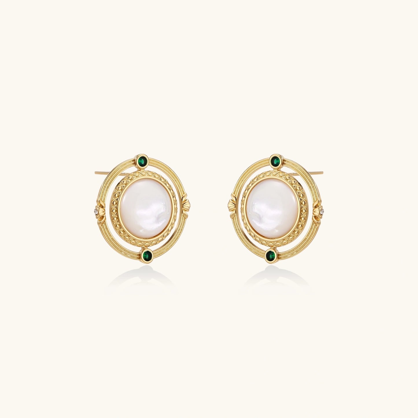 Circular gold stud earrings with iridescent mother-of-pearl center and green zirconia accents on cream background.