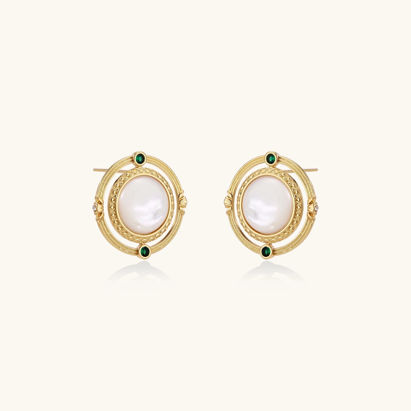 Circular gold stud earrings with iridescent mother-of-pearl center and green zirconia accents on cream background.