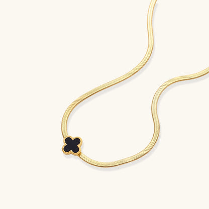 Dainty 18K gold-plated herringbone chain necklace with black enamel quatrefoil clover pendant on white background