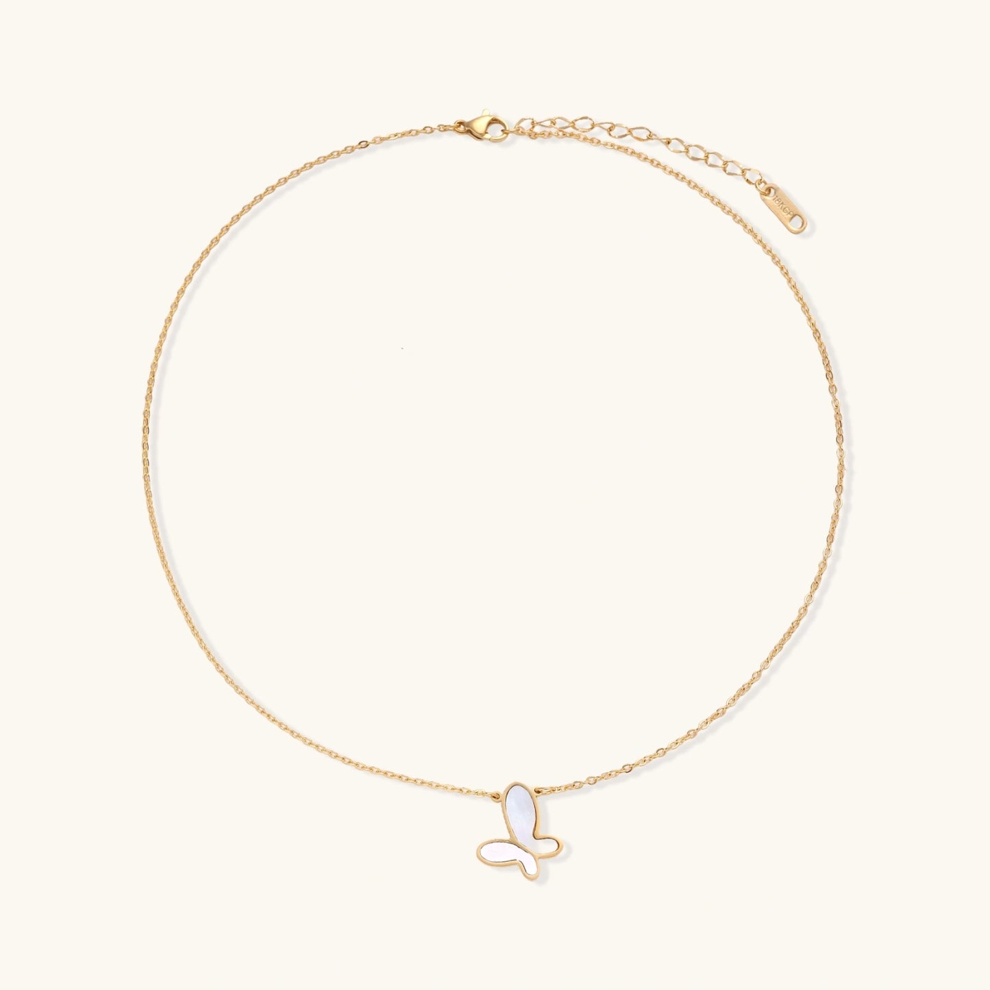Gold-plated butterfly pendant with iridescent mother of pearl inlay on delicate chain against cream background.